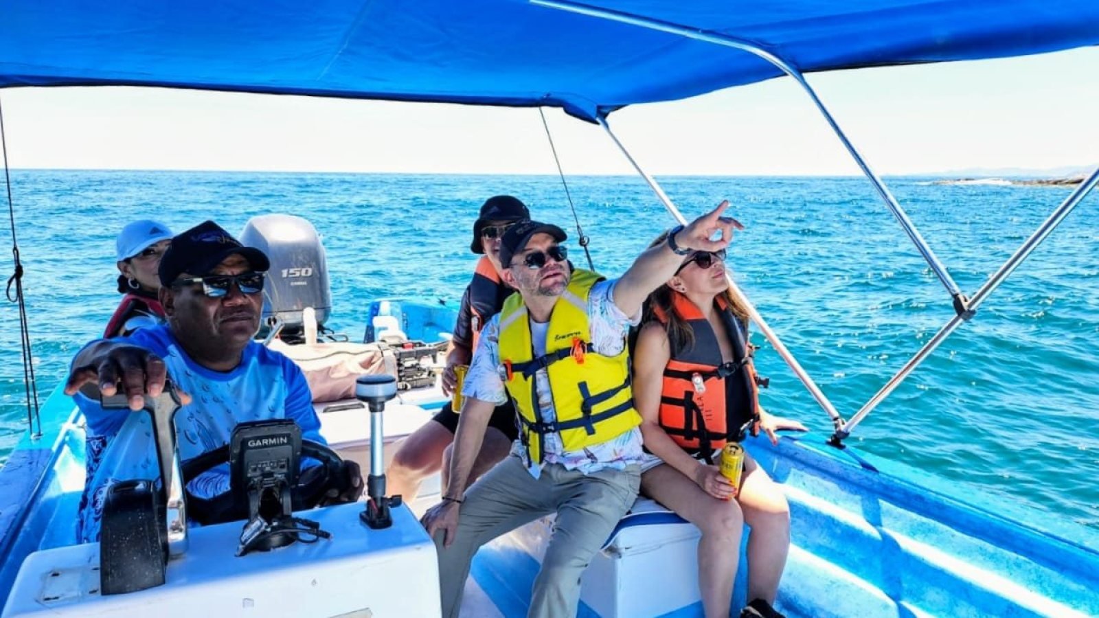Pasajeros con chaleco salvavidas bajo el toldo bimini de la panga Loreto Star, buscando ballenas en la Bahía de Loreto